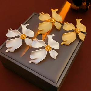 Close-up of vintage matte flower stud earrings in white and gold on a jewelry box