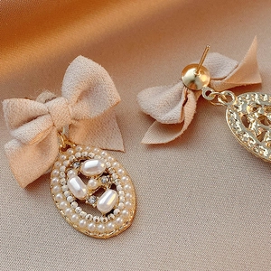 Detail of vintage bow earrings with faux pearls and rhinestones on champagne satin