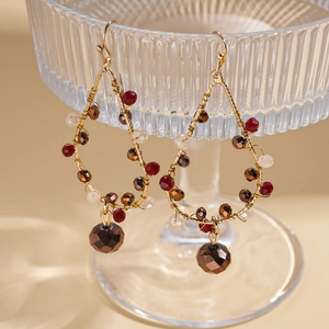 Détail de boucles d'oreilles goutte dorées avec perles de verre marron et crème