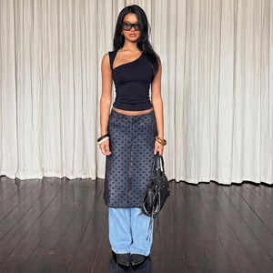 Fashionable black one-shoulder slim top styled with sheer skirt and denim jeans