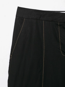 Detail of black straight pants featuring contrast stitching and side pocket texture