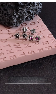 Macro detail of gothic star earrings with black, red and white gems on copper silver plating