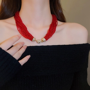 Macro detail of multi-strand red bead necklace with luxury gold rhinestone magnetic clasp