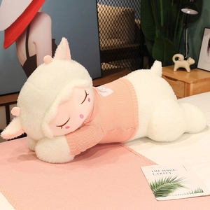 Detail of a large white sleeping plush sheep wearing a pink knitted sweater in a cozy bedroom