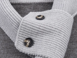 Dettaglio del cardigan in maglia grigia con trama fine e bottoni tartarugati scuri