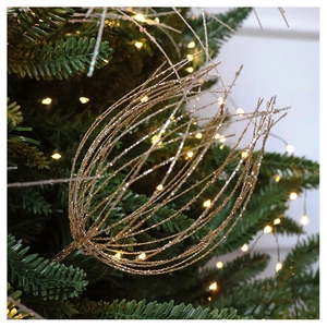 Detail of a sparkling gold hollow Christmas branch decoration on green tree branches