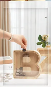Detail of wooden letter B piggy bank with coins being dropped into the acrylic panel