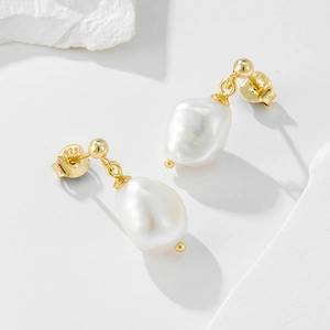 Elegant 925 sterling silver earrings with natural baroque pearls on white stone surface