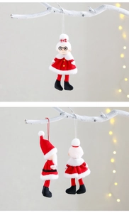 Detail of plush Santa and Mrs. Claus hanging ornaments on frosted branches with warm lights