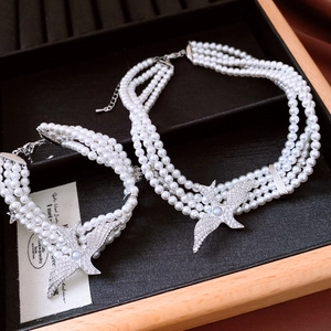 Detailed view of layered pearl necklace and eagle pendant in a wooden jewelry box