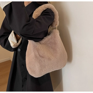 Furry beige tote bag with gold ring handles shown on a black coat outfit context