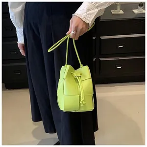 Detail of neon green woven leather mini bucket bag with drawstring closure and fine straps