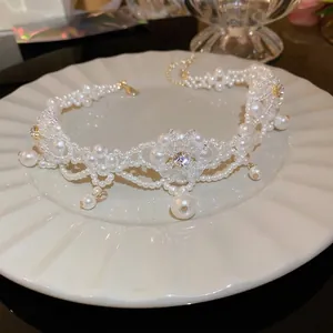 Elegant floral pearl choker necklace with crystal center displayed on a white plate