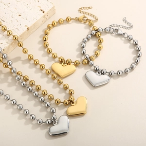 Detailed flat lay of heart pendant bead necklaces and bracelets in gold and silver steel