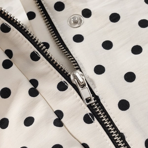 Close-up of polka dot jacket with metallic zipper and snap button detail