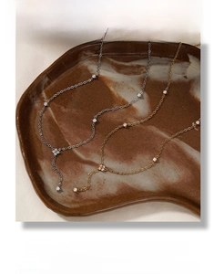 Detail of silver and gold heart zircon necklaces with Y-shape drop design on ceramic plate
