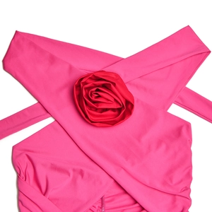 Detail of rose red dress featuring 3D floral accent and criss-cross halter straps