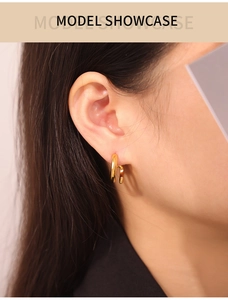 Detail of a minimalist double-layered U-shaped gold plated titanium steel earring on model
