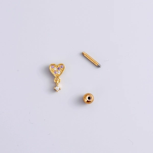 Puce d'oreille cœur doré avec cristaux roses et clairs sur fond blanc pur