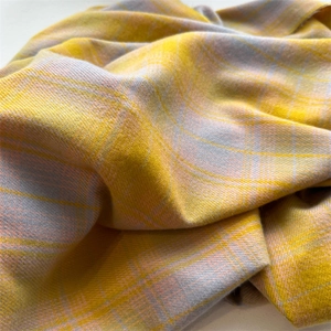 Macro detail of soft plaid fabric in yellow and grey-blue tones with classic tassel texture