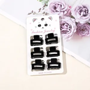 Close-up of six small black square hair claws on a fashion display card