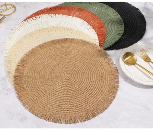 Dettaglio di tovagliette tonde intrecciate con frange in vari colori su marmo