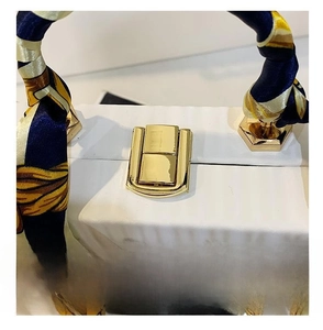 Detail showing the golden metal lock and elegant printed silk scarf on the white handbag