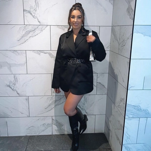 Detail of black blazer dress featuring a wide eyelet studded belt and chic silver handbag