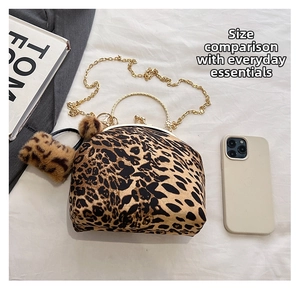 Detail view of leopard print shell bag with gold handle, chain strap and plush charm