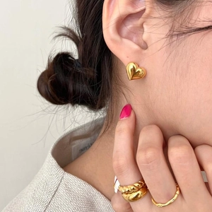 Close-up of S925 gold-plated heart earring and twisted metal rings on model