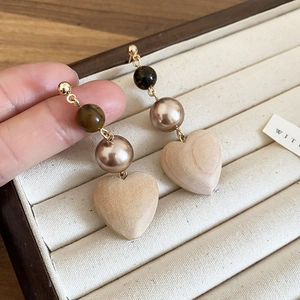 Detail view of heart-shaped wooden drop earrings with beaded metallic accents