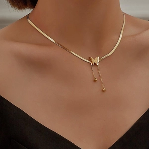 Close-up of golden butterfly fringe pendant necklace on a flat snake bone chain