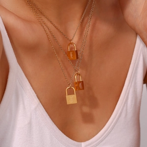 Close-up of triple-layered gold necklaces with engraved lock pendants on model