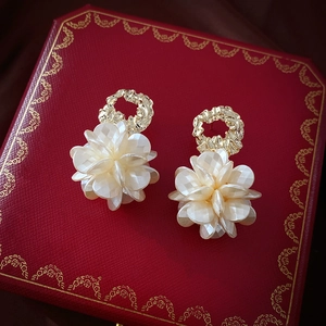 Detail of vintage acrylic flower earring with gold metallic ring on a red jewelry box