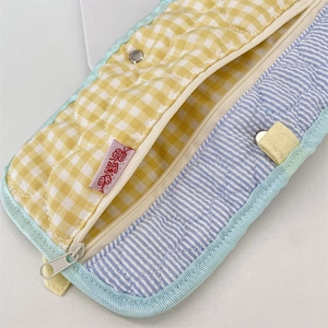 Detailed close-up of quilted fabric organizer with yellow gingham and blue stripe patterns