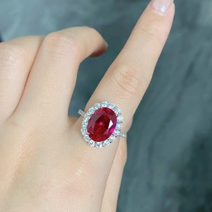 Macro view of a silver halo ring featuring an oval red ruby and sparkling zircon accents