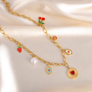 Detail view of gold chain necklace with colorful cherry and strawberry charms on silk