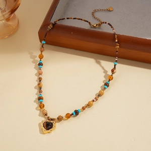 Retro tiger eye beaded necklace featuring a golden heart pendant on a wooden tray
