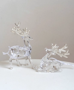 Close-up of clear acrylic reindeer figurines with silver glitter on antlers and hooves