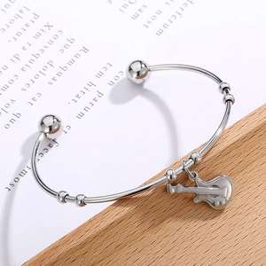 Detail shot of a silver open guitar bangle showing the musical instrument pendant close up