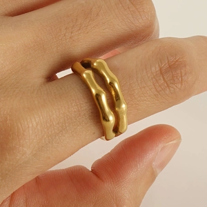 Detail of a chunky gold bamboo-shaped wave ring worn on finger for a stylish look