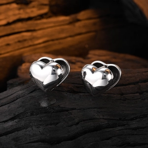 Detail shot of double heart-shaped silver earrings with a high-polished mirror finish