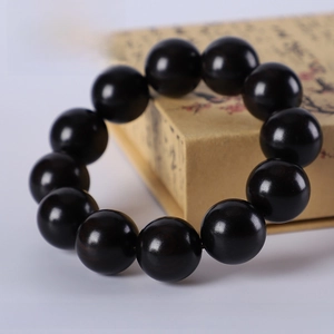 Macro detail of 20mm African Blackwood prayer beads on a premium traditional gift box