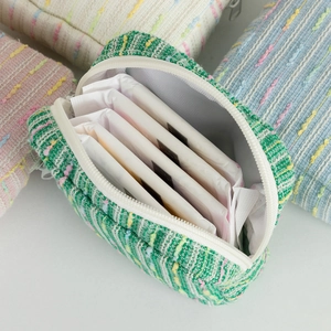 Detail of green tweed cosmetic bag with internal storage for feminine hygiene products