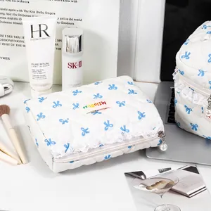 Premium quilted white makeup bag featuring cute blue bow patterns and elegant pearl zipper