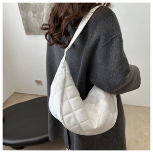 Detailed side view of white quilted hobo bag with wide strap on model's shoulder