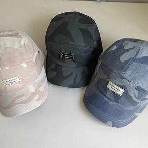 Detailed view of three vintage camouflage camp hats with rectangular woven labels