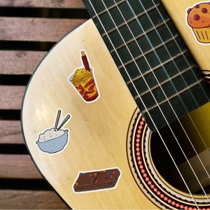 Cute food stickers showing cupcakes and drinks applied on a wooden guitar surface