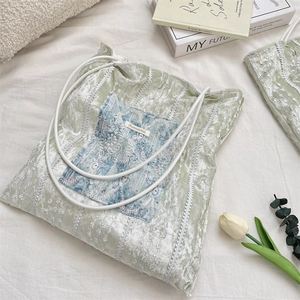 Detailed close-up of light green velvet tote bag with white lace trim and floral patches