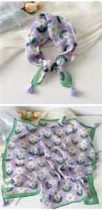 Detail view of cotton linen scarf with floral print and purple tassels in flat lay